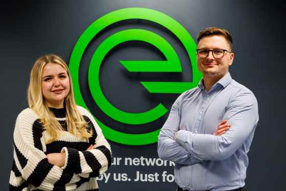 Man and a women standing in front of an evolving networks sign