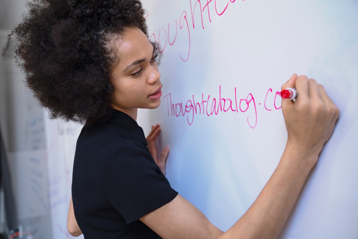 Lady writing on whiteboard in red pen