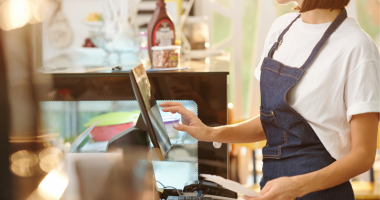 Woman wearing apron at a cash desk 