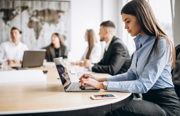 Female office worker on laptop with colleagues 