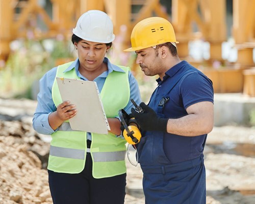 Construction Manager And Worker On Site Looking At Clipboard