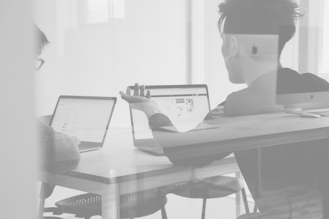 Two People working On Laptops and Talking