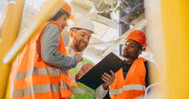 Three construction workers in high viz reviewing clipboard 