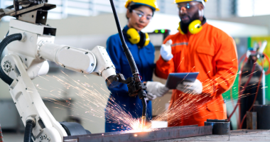 Male and female factory workers overseeing welding machine