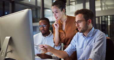 Female worker and two male colleagues reviewing computer screen