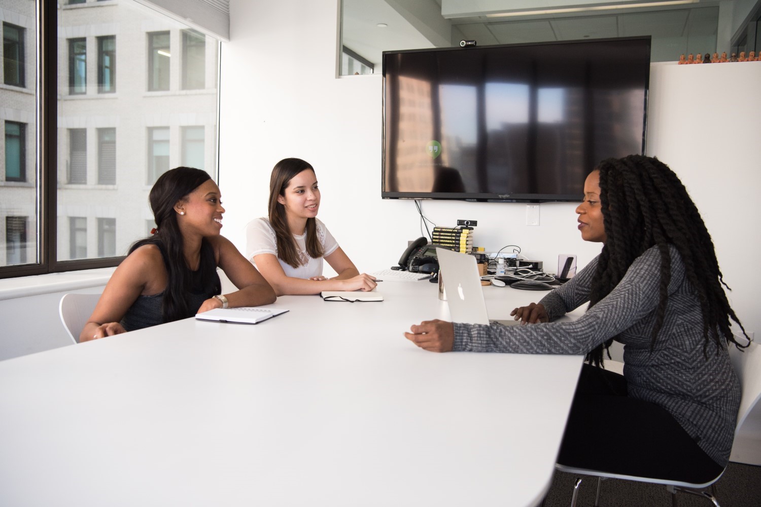 Three women sitting at a desk having a Group Meeting